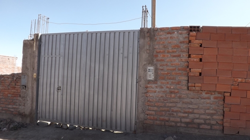 Vivienda en Arequipa de Yovana Mendoza. Tras el muro hay una casa de dos pisos con jardía